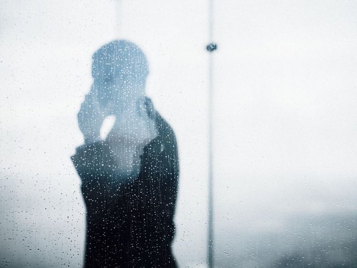 Side view of a silhouette man against waterdrops on glass