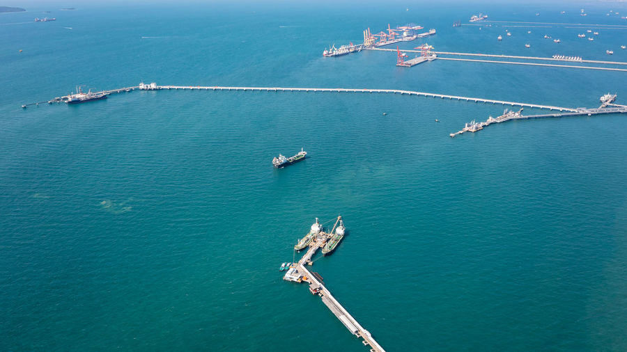 Aerial view oil pipes to oil tanker ships at pier off the coast in beautiful peaceful environment 
