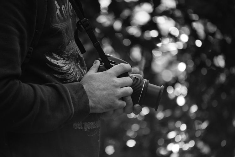 Midsection of man holding camera 