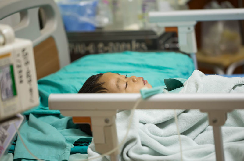 High angle view of cute boy lying on bed in hospital