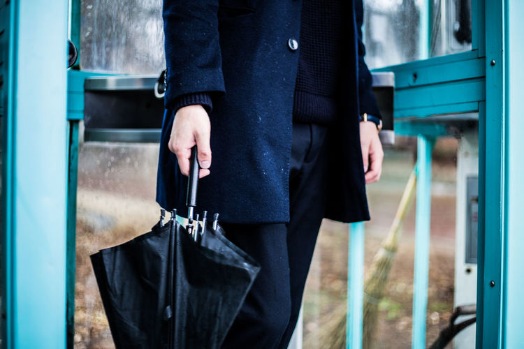 Midsection of man holding umbrella