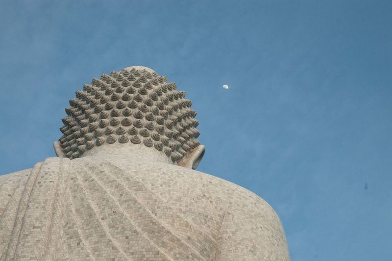 Low angle view of buddha statue against sky at dusk