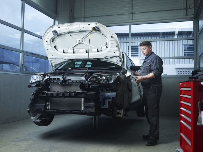 Mature expert installing car parts at auto repair shop