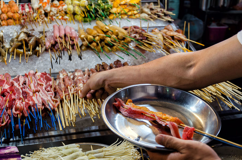 Counter with chinese street food,  buyer  with food on sticks. malaysia, kuala lumpur, jalan alor.
