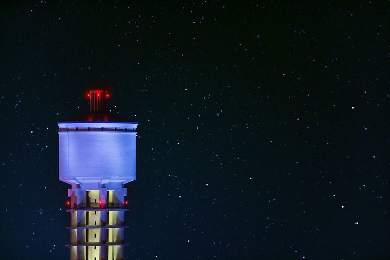 Illuminated water tank against star field at night