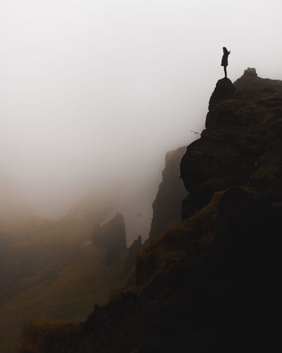 Silhouette rocks on mountain against sky during foggy weather