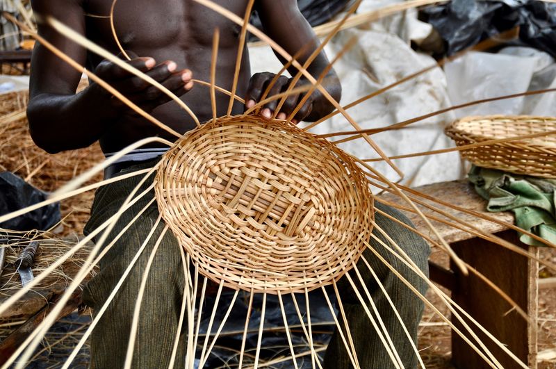 Midsection of man weaving wicker basket