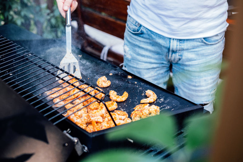 Grilling shrimp on skewer on outdoor grill. grilled shrimps on the flaming grill. man hand using