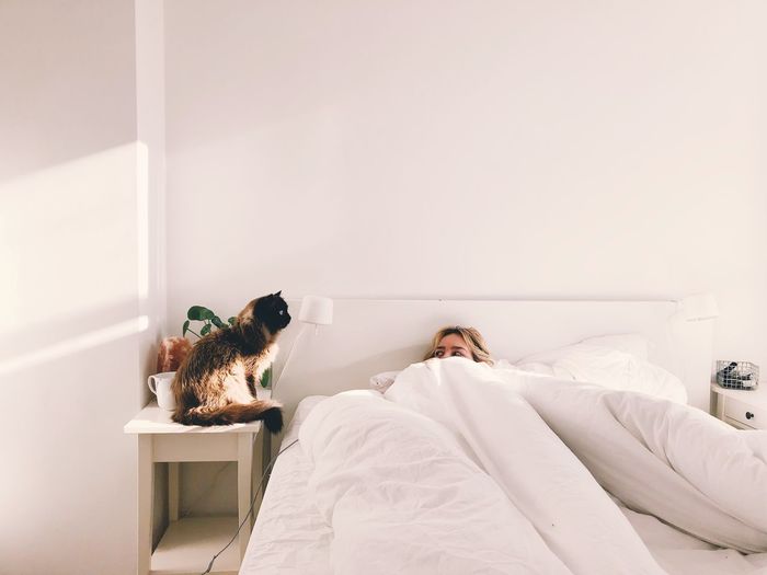 Cat sitting next to woman in bed