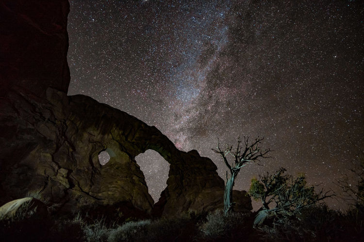 Low angle view of rock formation against star field at night
