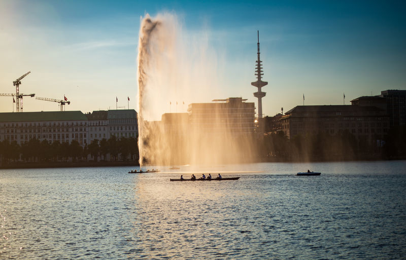 A four skiff team rows past the water fountain on the binnenalster lake 