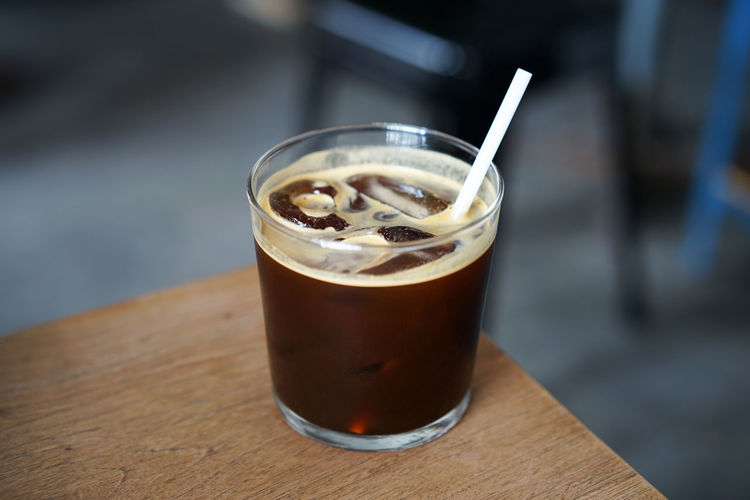 Close up glass of iced black coffee on wooden table