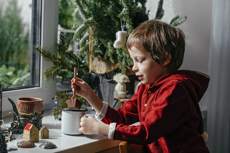 Side view of cute girl blowing christmas tree at home