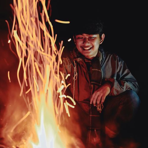 Smiling man sitting by campfire