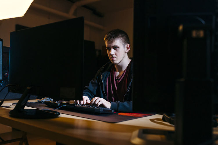 Young computer hacker working while sitting at office
