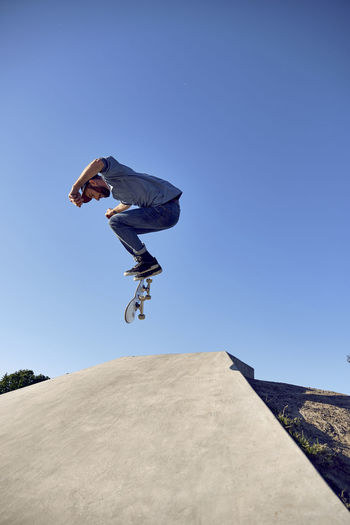 Skateboarder doing kickflip on concrete ramp