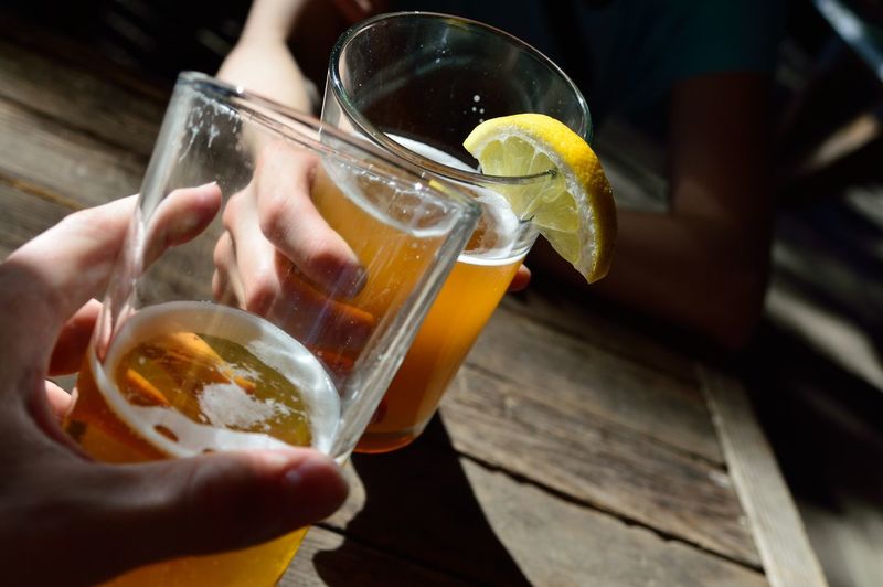 Cropped image of hand toasting beer glasses at table