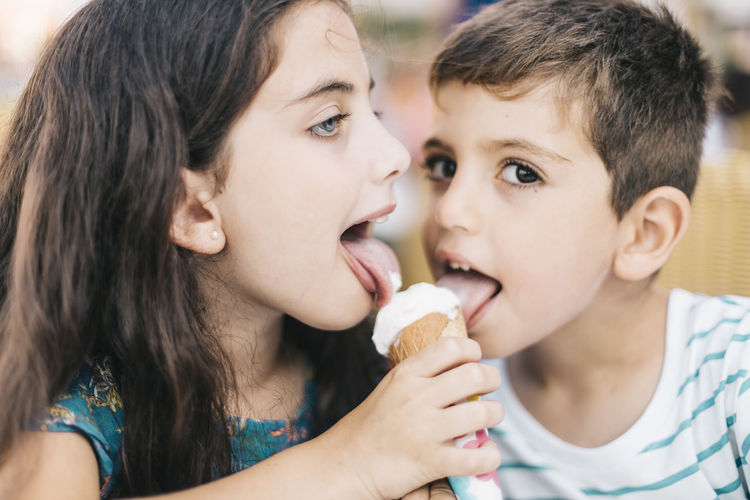 Portrait of siblings licking ice cream