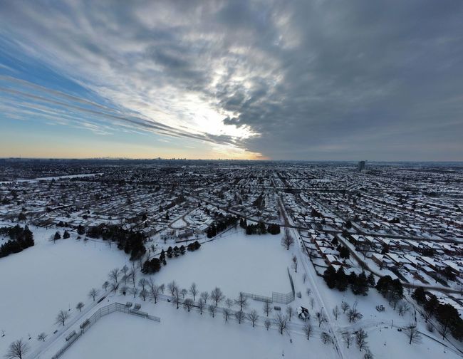 Aerial view of snow covered landscape against sky during sunset