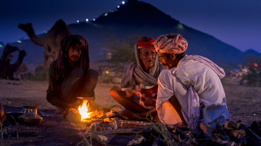 Group of villagers restng by camp fire at night at camel fair
