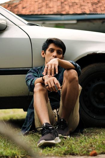 Portrait of young man sitting on car