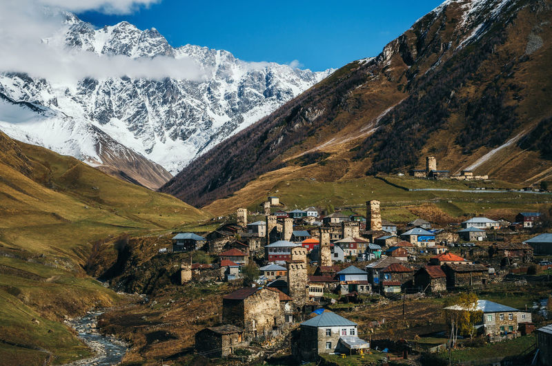 Village by snowcapped mountains against sky