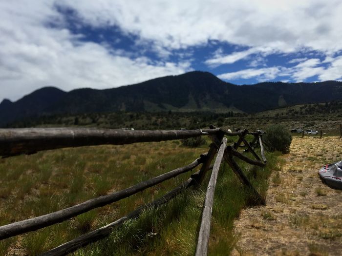 Fence on field by mountains against sky