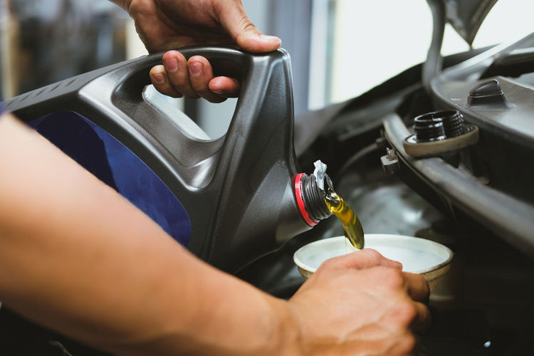Cropped hand pouring oil in vehicle engine