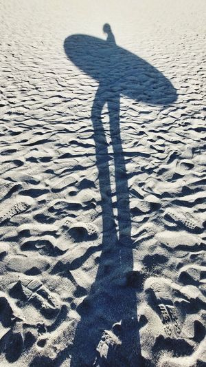 Shadow of man walking on sand at beach