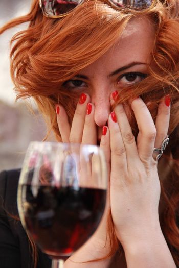 Portrait of woman covering mouth with red wine in foreground