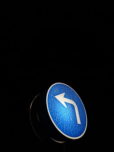 Close-up of road sign against black background