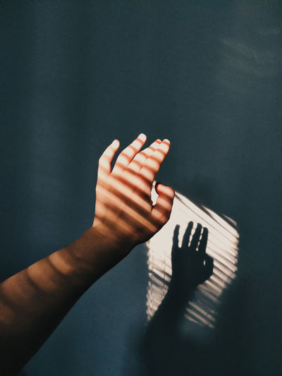Cropped hand of woman with shadow against wall