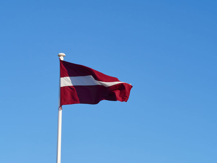The national flag of latvia waving in the wind on the flagpole. horizontal frame.