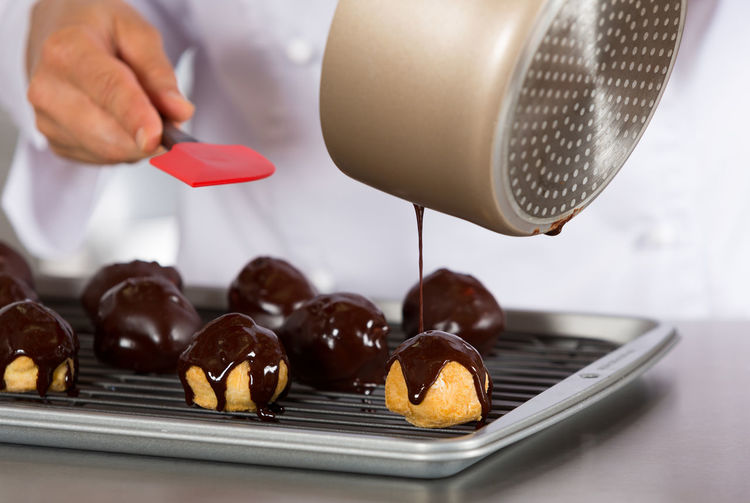 Midsection of chef pouring chocolate sauce on dessert in baking sheet