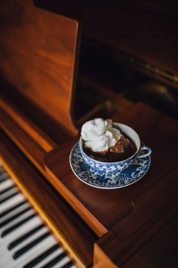 Hot chocolate in japanese blue and white teacup atop a baby grand piano