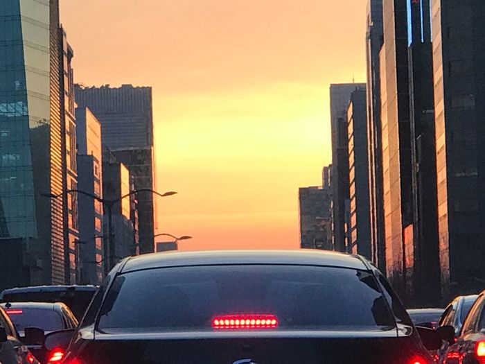 Cars on city against sky during sunset