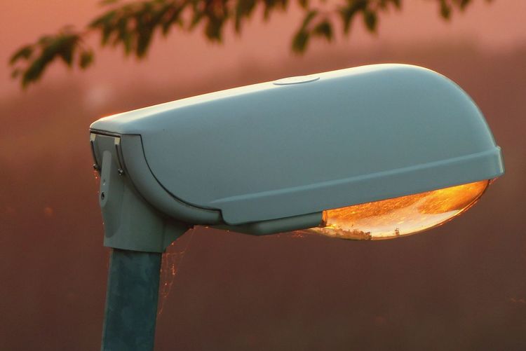 Close-up of illuminated lighting equipment against sky during sunset