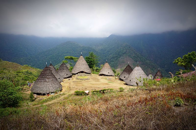 High angle view of traditional houses on hill against mountains during foggy weather