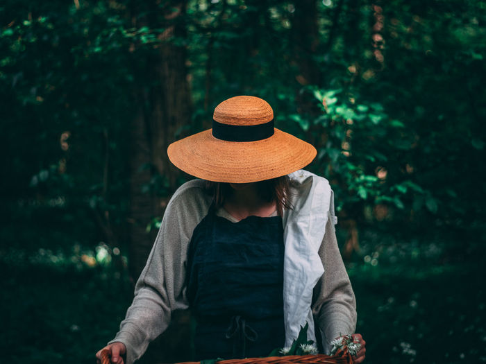 Rear view of woman wearing hat standing against plants