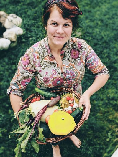 Portrait of smiling mid adult woman with vegetables in basket on field