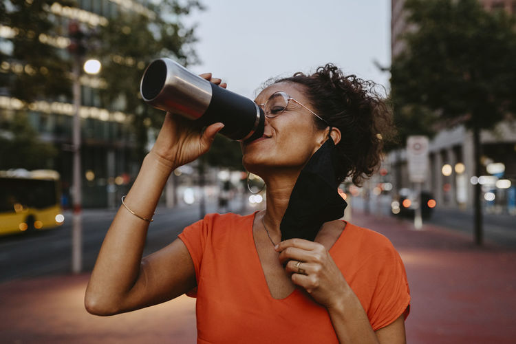 Portrait of beautiful young woman drinking man in city