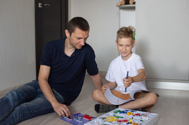 White t-shirt, electrical designer, lots of details, boy and man, dad and son, sit on the floor