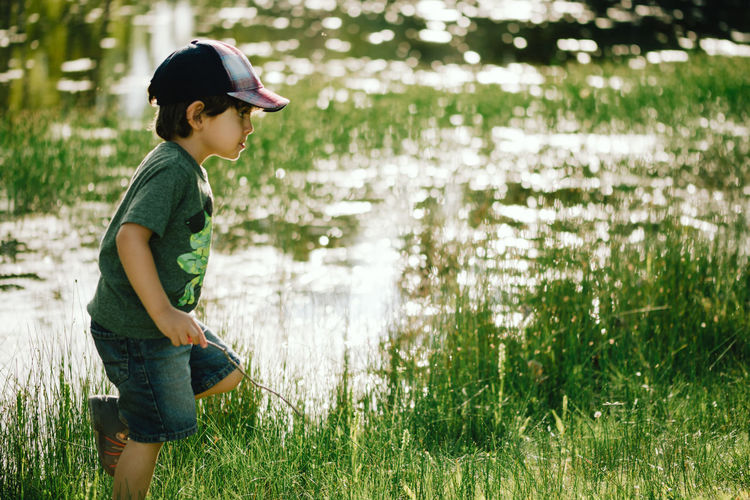 Profile view of boy walking on grassy lakeshore