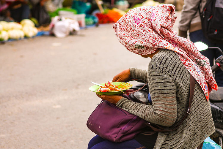 A woman of the batak ethnic tribe eating her lunch at the side of the street market