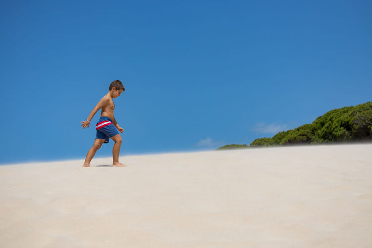 Little boy walking down a dune on a spanish beach