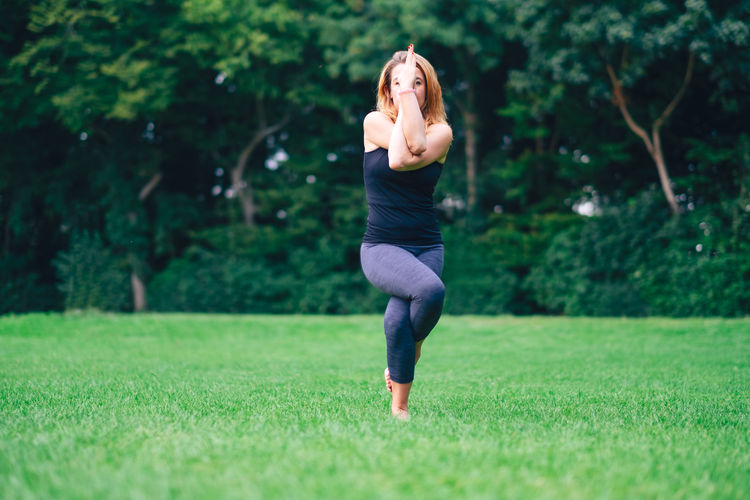 Woman in park practicing yoga in nature on grass with barefoot