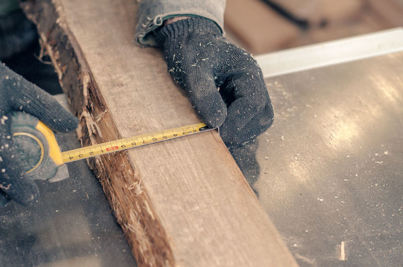 Carpenter measures width of board with carpenter's meter.