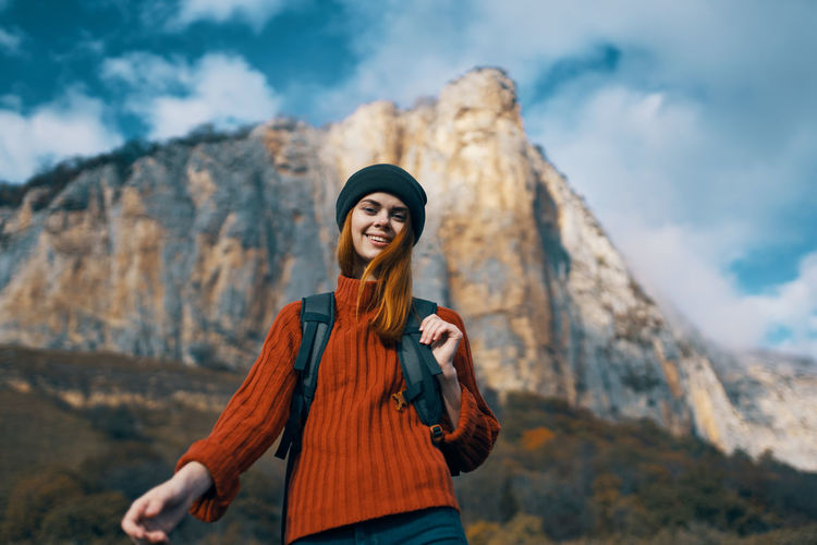 Young woman wearing hat standing against mountain