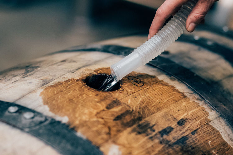 Filling american oak barrel with white dog whiskey, moonshine to age in bourbon whiskey production
