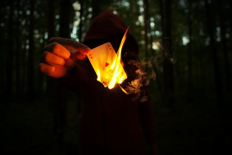 Close-up of person burning ace card in forest